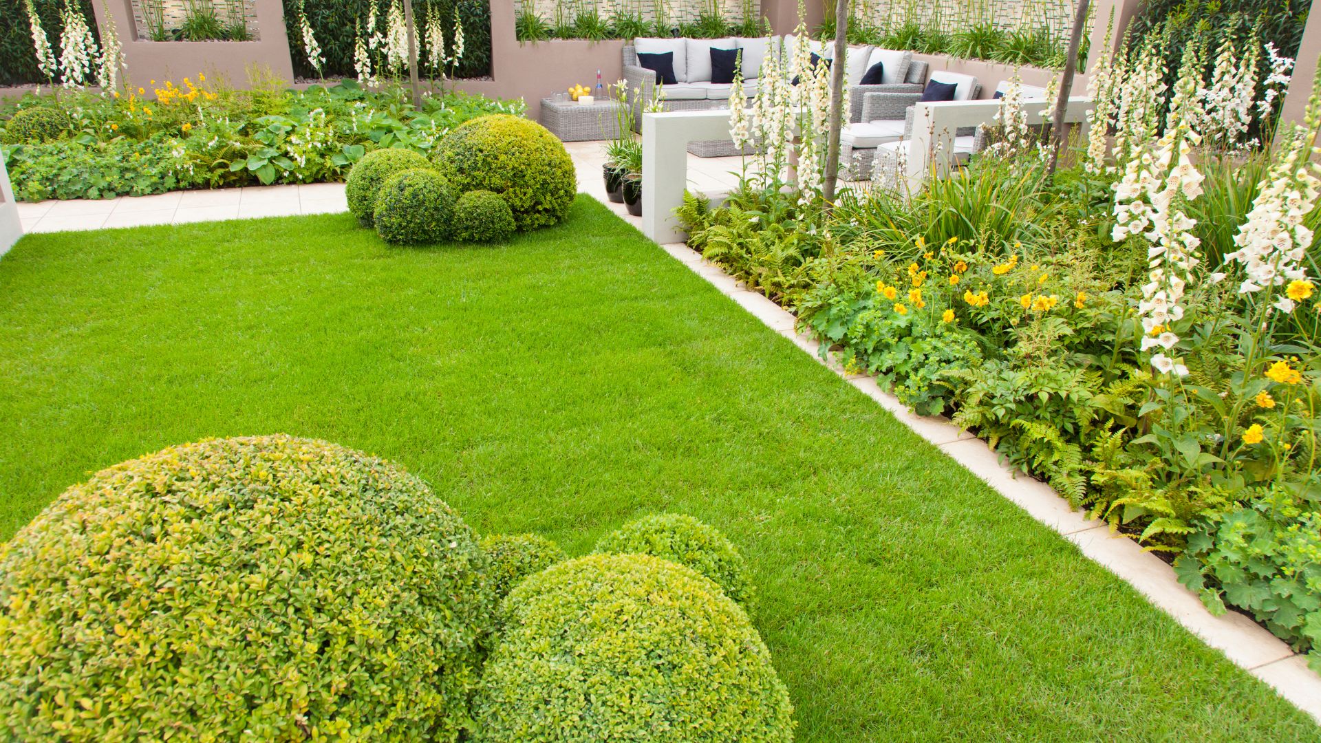 Manicured garden with green lawn, topiary bushes, and seating area
