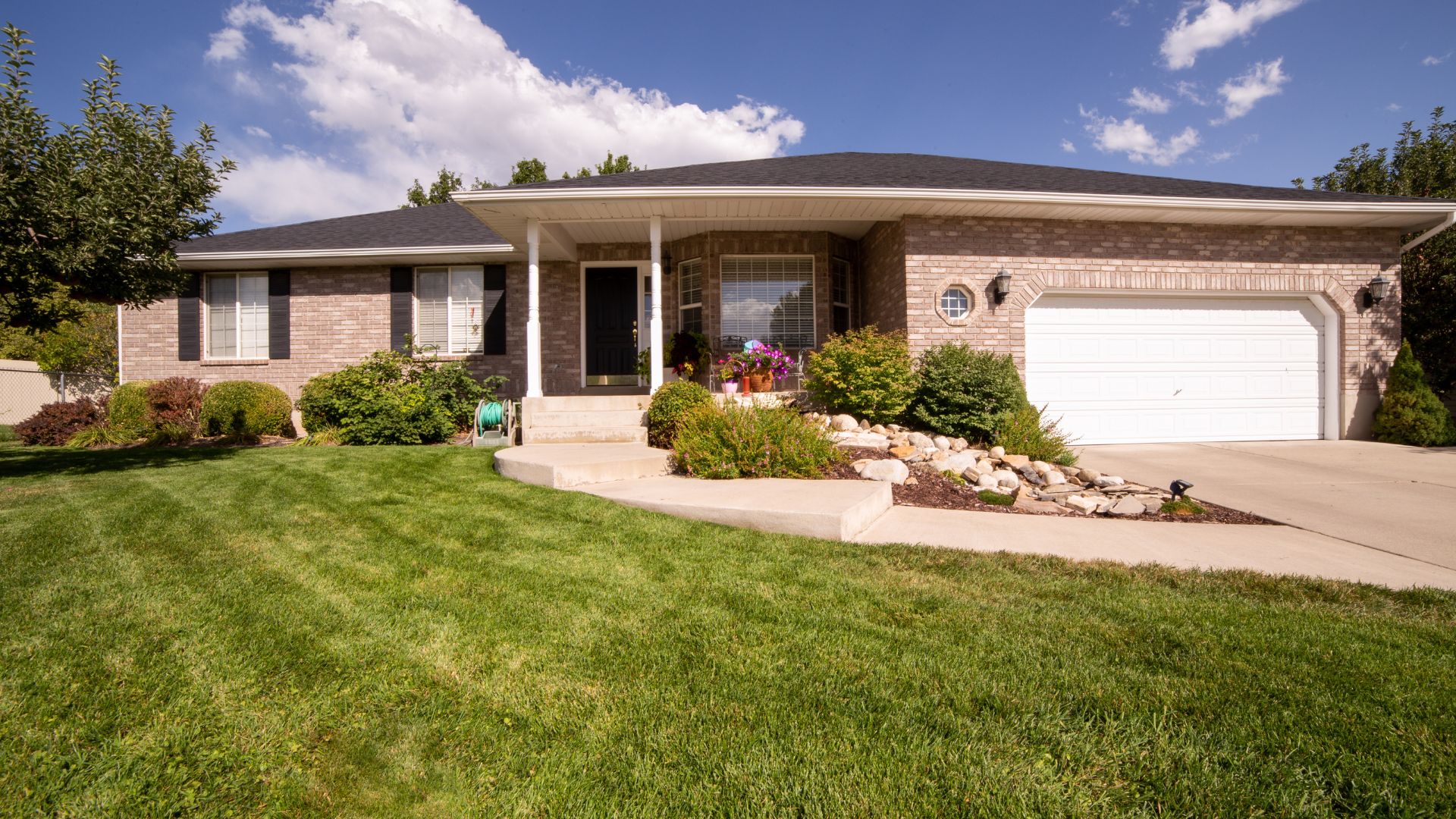 Suburban brick ranch house with manicured lawn and rock garden landscaping