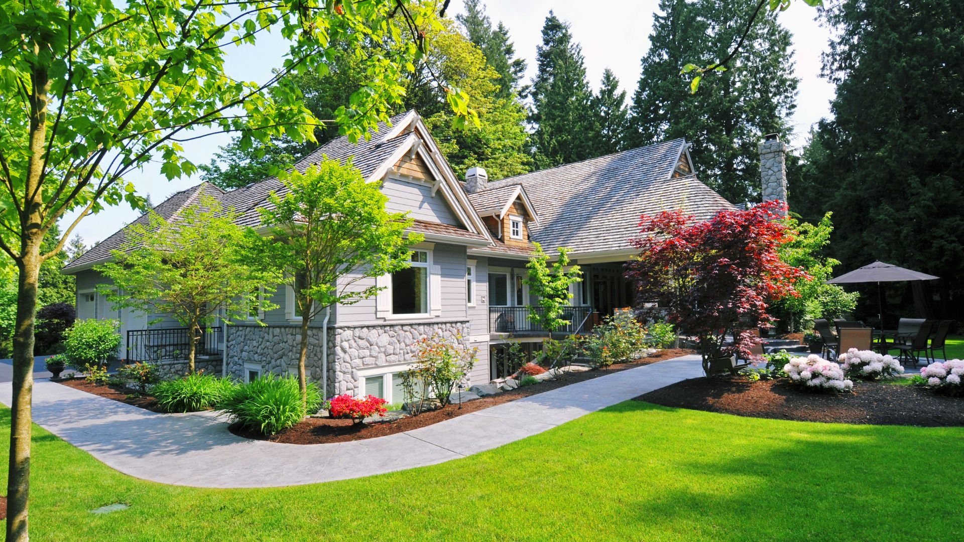 Well-manicured suburban home with stone exterior and lush green landscaping